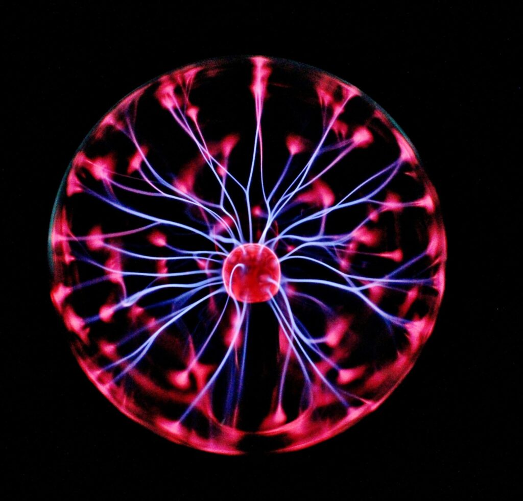 Close-up of a plasma globe with vibrant neon sparks against a dark background.