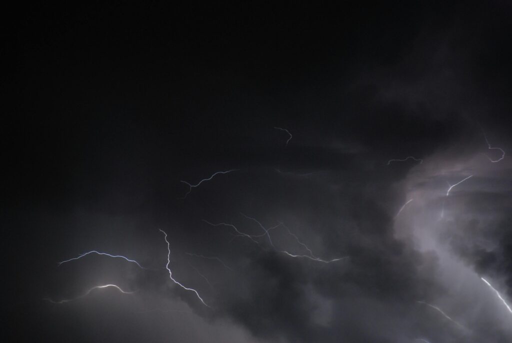 Intense lightning flashes illuminate a dark sky during a powerful thunderstorm.